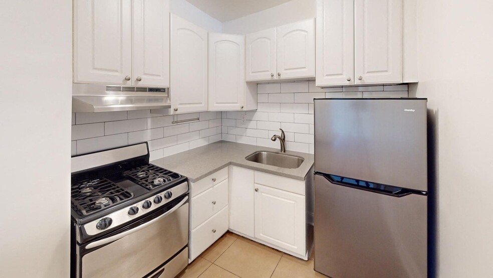 Kitchen with multiple cabinets, refrigerator, stove, range hood, and sink - 645 Stockton Street