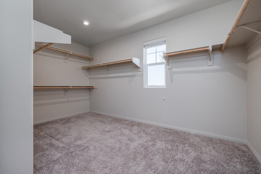 Spacious walk-in closet in the primary suite featuring built-in shelving - 26549 Brightstone Dr