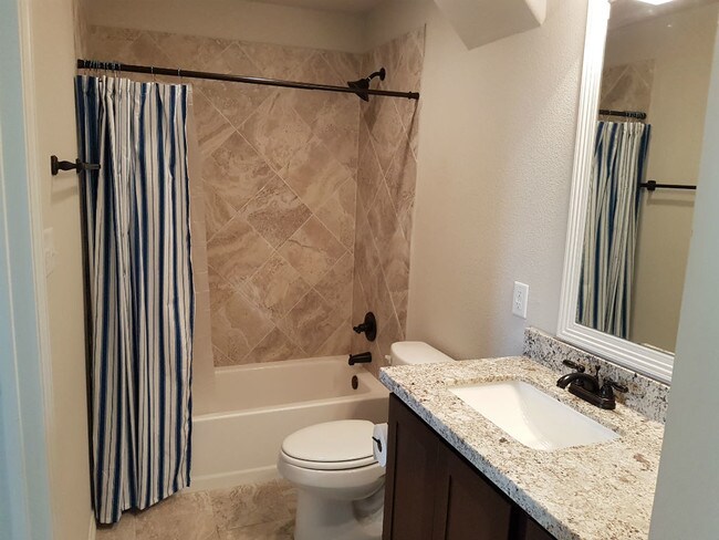 Bathrooms include granite counter-tops and tile showers with built-in corner shower shelves and modern fixtures. - 113 Ehlinger Dr